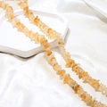 Macro view of irregular amber citrine crystal beads on white silk and marble display - 1 Piece / Orange