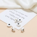 Macro detail of smiley face ceramic flower beads for DIY jewelry making on card - White Black Smiley Small Flower