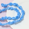 Macro view of blue heart ceramic beads with pearlescent glaze for DIY jewelry making - Blue