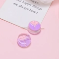 Detailed macro view of two pastel purple and pink resin beads on a gold metal pin - Purple Pink Peace Round