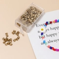 Macro shot of gold triangular spacer beads in a clear storage box for DIY jewelry making - 10g Per Box / Gold