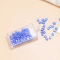 Vista macro di perle cubiche in vetro smerigliato blu chiaro da 4 mm con contenitore - Viola