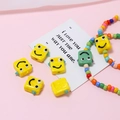 Detail von gelben und grünen Roboter-Smiley-Glasperlen für die DIY-Schmuckherstellung - Roboter-Form / Gelb