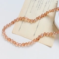Gros plan de perles en verre facetté ambre avec reflets champagne sur papier vintage - Style Facetté Classique / Ambre Iridescent