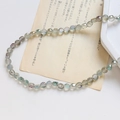 Macro de perles de cristal de verre facettées irisées gris-vert sur fond de papier vintage - Style Facetté Classique / Gris Vert Iridescent