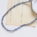 Gros plan de perles en verre de cristal facetté bleu-gris sur papier vintage - Style Facetté Fin / Bleu Gris Iridescent