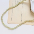 Détail de perles en cristal facetté vert menthe disposées en courbe S sur papier vintage - Style Facetté Fin / Vert Menthe Iridescent