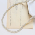 Vue macro de perles en cristal blanc irisées facettées sur papier vintage rétro - Style Facetté Fin / Blanc Laitueux Iridescent