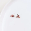 Macro view of red and silver wing-shaped enamel earrings on a white ceramic plate - White K Rabbit Ear