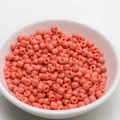 Macro view of 4mm coral orange round seed beads in a white bowl for DIY jewelry making - 4mm / Orange Pink