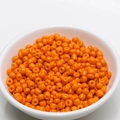 Top view of 4mm orange ceramic seed beads in a white bowl for DIY jewelry making - 4mm / Orange