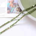 Macro detail of translucent green oval glass beads with gold spacers on a stylish magazine - Dark Green