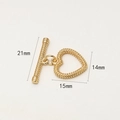 Makroansicht des vergoldeten Herz-Knebelverschlusses mit körniger Textur und Maßen - Granulares Herz