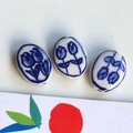 Macro shot of three oval ceramic beads with hand-painted blue tulip patterns for DIY jewelry - 3# Blue Double Flower Oval Large