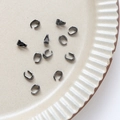 Vue macro de bélières gris fusil et connecteurs de pendentif sur plat en céramique - Bélières Noir Fusil