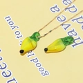 Macro shot of a yellow glass banana pendant with green stem on a gold chain necklace - Banana