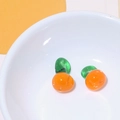Macro shot of two orange fruit glass beads for DIY jewelry making in a white bowl - Persimmon