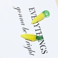 Macro detail of glass corn-shaped charms with yellow kernels and green leaves for DIY jewelry - Corn