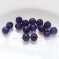 Macro detail of deep purple crystal glass round beads with a gold needle showing hole size - Starry Purple