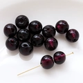 Macro shot of dark purple glass beads with gold foil texture for DIY jewelry making - Red Black
