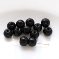 Macro shot of polished black glass beads with gold T-pins for DIY jewelry making - Black