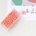 Macro shot of peach pink glass seed beads in a clear box for DIY jewelry making - Pink