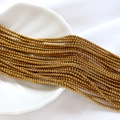 Gros plan de perles de rocaille en verre bronze 2mm sur un plat en coquillage pour bijoux DIY - Style Doré