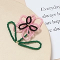 Dettaglio macro di accessorio floreale fatto a mano con perle rosa e foglie verdi - Rosa