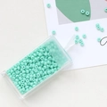 Macro shot of mint green glass seed beads for DIY jewelry making in a plastic container - Green