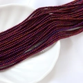 Détail macro de perles de verre violettes 2mm à effet irisé sur un plateau blanc - Style Rouge Pourpre Foncé Iridescent