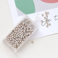 Detailed macro of cream macaron glass seed beads in a transparent rectangular plastic box - Gray