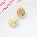 Detalle de pendientes de cuentas crema con base de metal dorado en plato de cerámica - Beige
