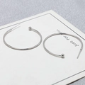 Detail view of silver S925 C-shape hoop earrings with metal beads on a display card - 35mm / White Gold