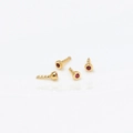 Vue macro détaillée de quatre mini clous d'oreilles dorés avec zircons rouges sertis - Or K Zircon Rose