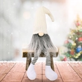 Gnome de Noël avec long bonnet en tricot blanc et jambes rayées dans un décor de neige - Poupée sans visage assise blanche