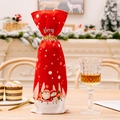 Housses de bouteille de Noël rouges avec motifs Père Noël et ruban doré sur table festive - Pois de Noël