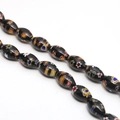 Macro shot of oval Millefiori glass beads with colorful floral patterns on black base - Approx. 32 Pcs/Strand (8x13mm) / Black
