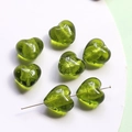 Macro detail of green glass heart beads with gold foil texture and cross-hole design - Green