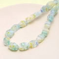 Macro detail of faceted light green glass beads with yellow and blue floral patterns - Multifaceted (Light Blue) (1 Strand)