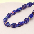 Macro detail of dark blue Millefiori glass beads with colorful floral patterns and stripes - Teardrop Shape (Royal Blue) (1 Strand)