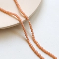Macro shot of 3mm faceted orange-pink crystal beads for DIY jewelry making and necklaces - Orange