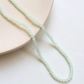 Detail of 3mm light green faceted crystal spacer beads on a cream ceramic plate - 4# Light Green