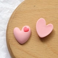 Nahaufnahme von matten rosa herzförmigen Harzanhängern für DIY-Schmuckherstellung - Rosa