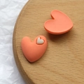 Detailansicht herzförmiger Harzanhänger in mattem Orange und Weiß auf einem Holztablett - Orange