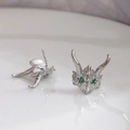 Macro detail of dragon head ear studs with green gemstone eyes and silver scales texture - White Gold