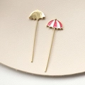 Macro shot of gold umbrella charms with red enamel details for DIY jewelry making - Pink
