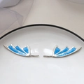 Detail of silver wing charms with blue drip oil and glitter inlay on a white tray - Devil Wing Platinum