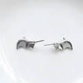 Detailed close-up of gothic silver bat wing stud earrings on a white porcelain edge - Small Bat Wings / White Gold