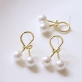 Gros plan de boucles d'oreilles nœud en or poli avec perles blanches et clous en argent S925 - Clous en Perles à Nœud