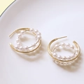 Détail macro de boucles d'oreilles nœud doré avec perles blanches et tige en argent 925 - Boucles d'oreilles clous en perles en forme de C